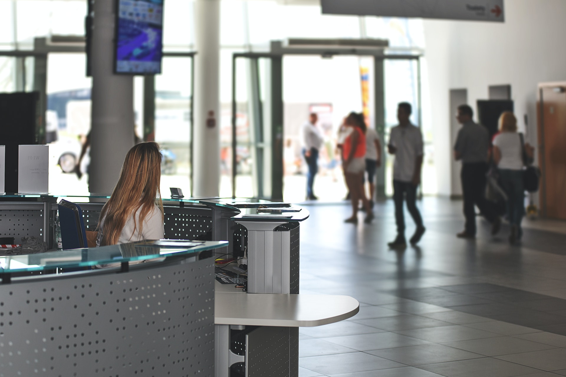 a receptionist sits at the desk in the entrance to a busy building