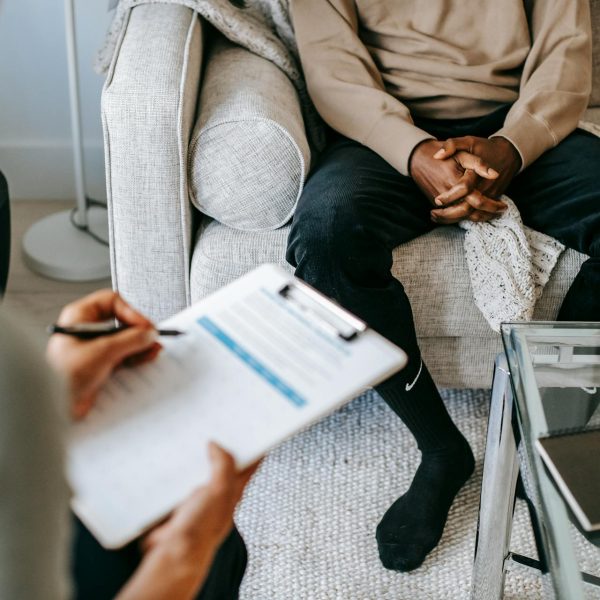 A psychologist writes on a clipboard while talking with a client.