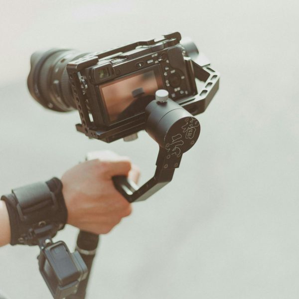 A person holds a DSLR camera with a stabilizer.