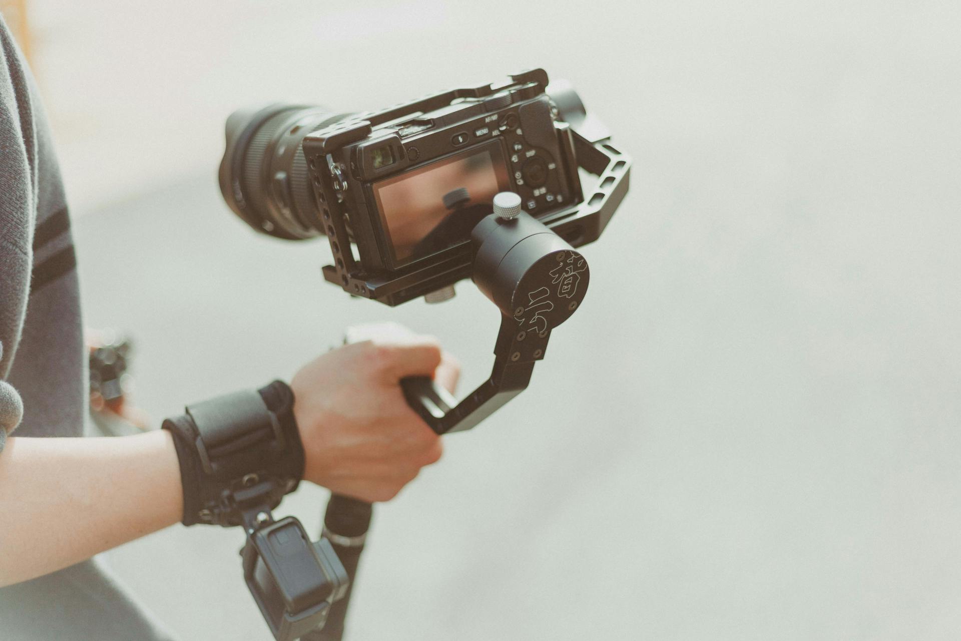 A person holds a DSLR camera with a stabilizer.