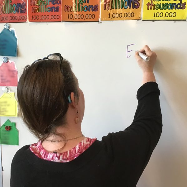 Rhonda writes with a marker on a dry erase board in her classroom.