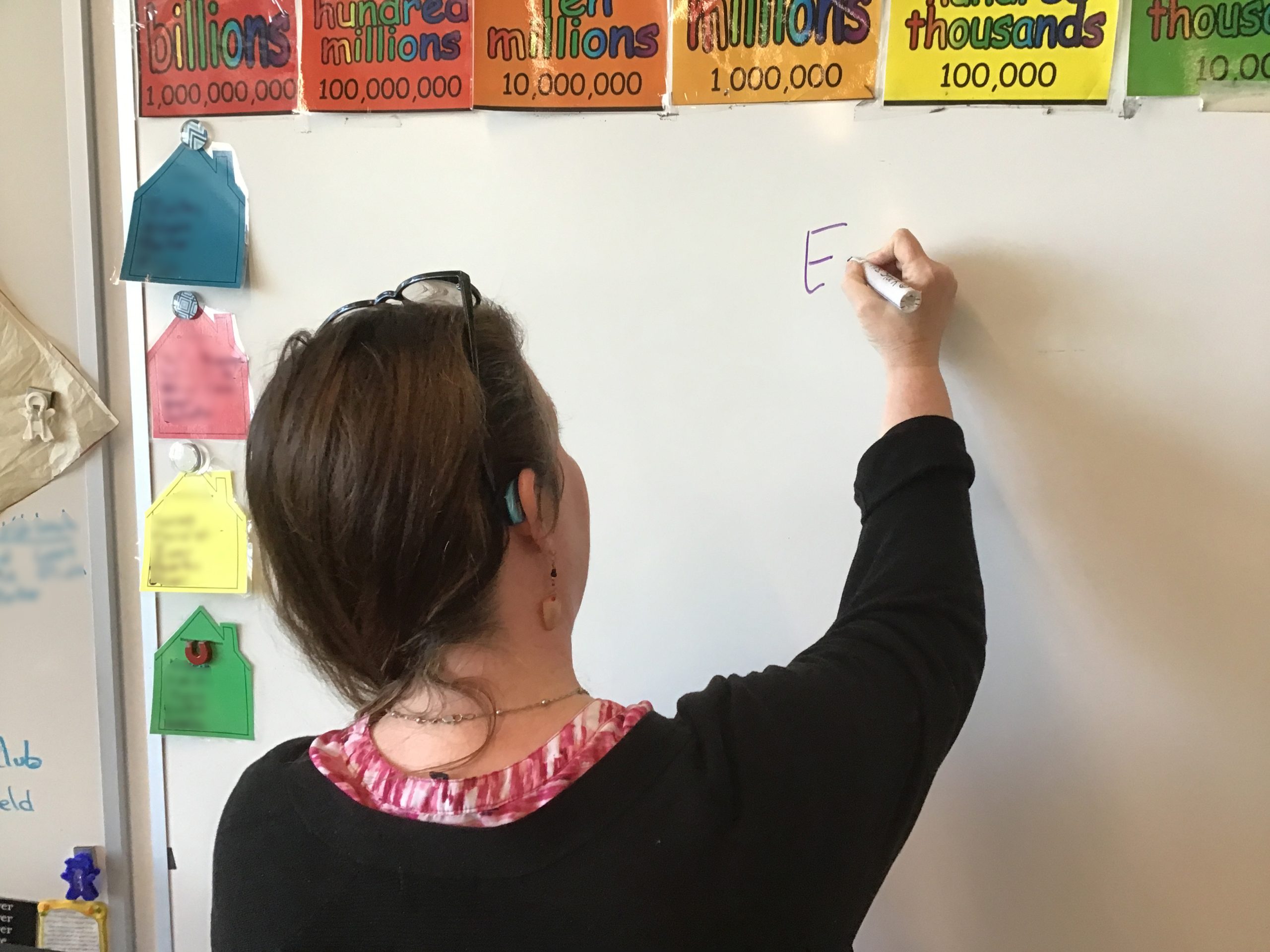 Rhonda writes with a marker on a dry erase board in her classroom.