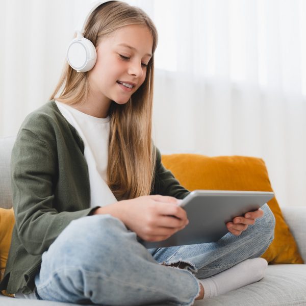 A girl wearing headphones uses a tablet.