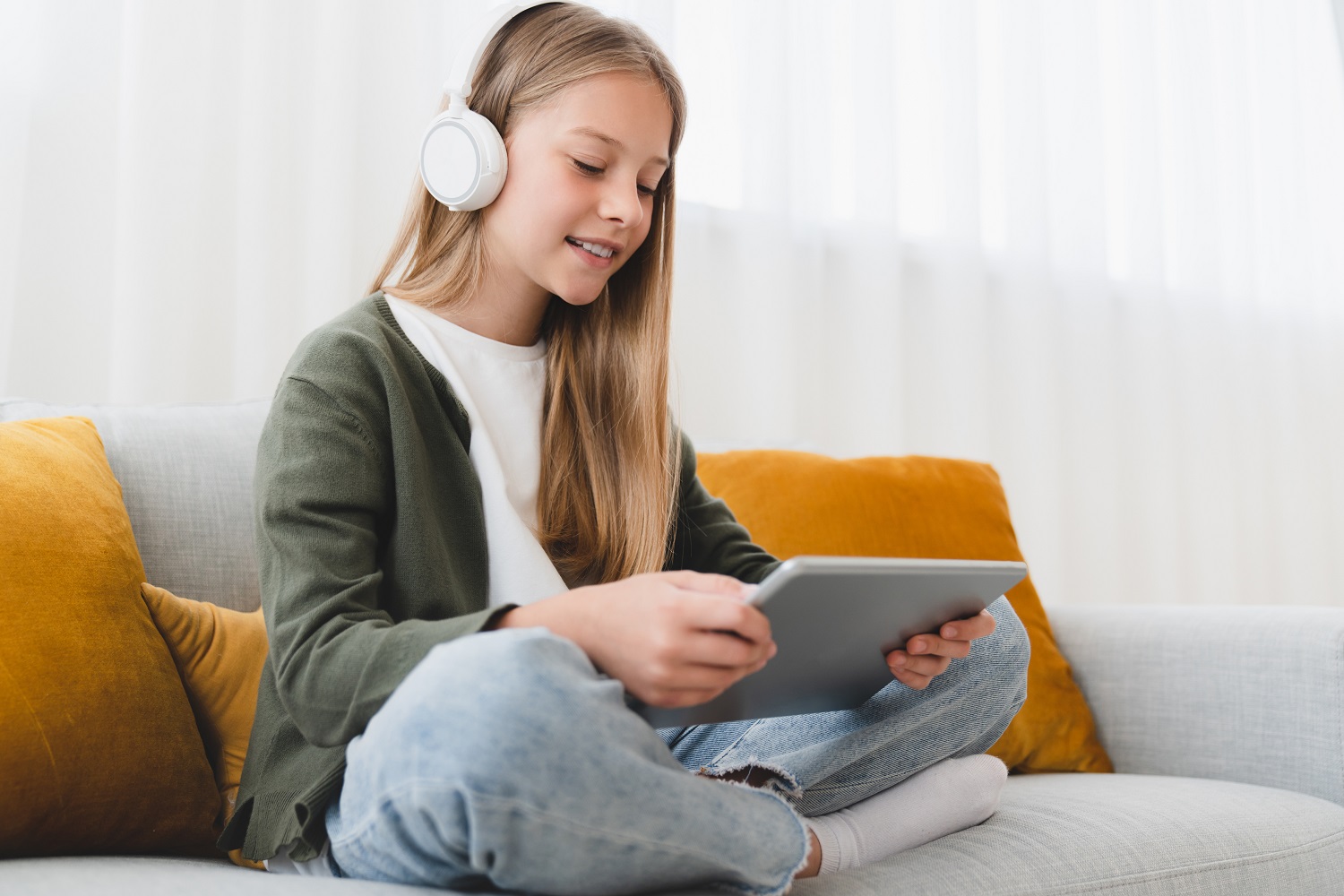 A girl wearing headphones uses a tablet.