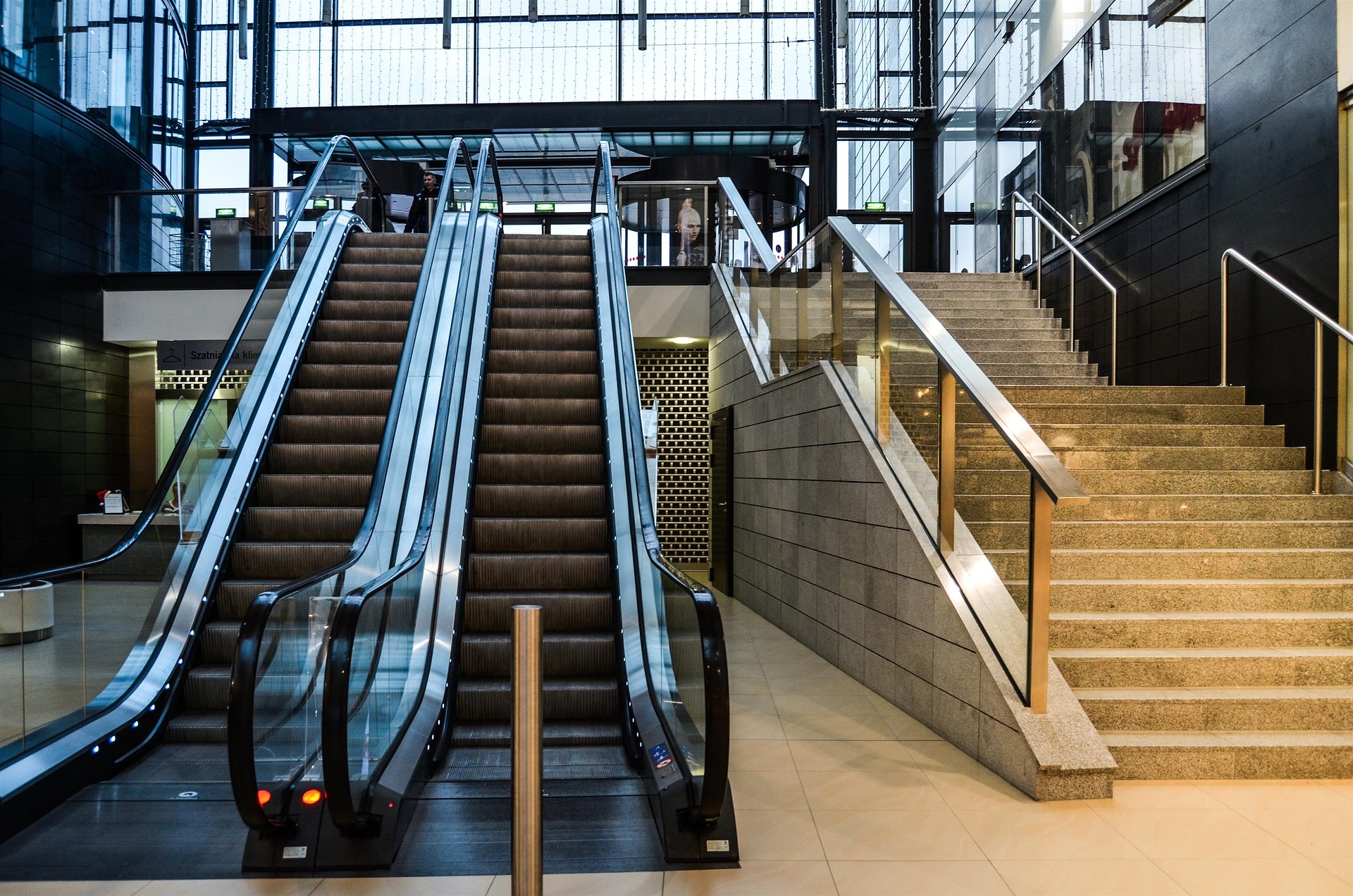 An escalator and a staircase in a mall.