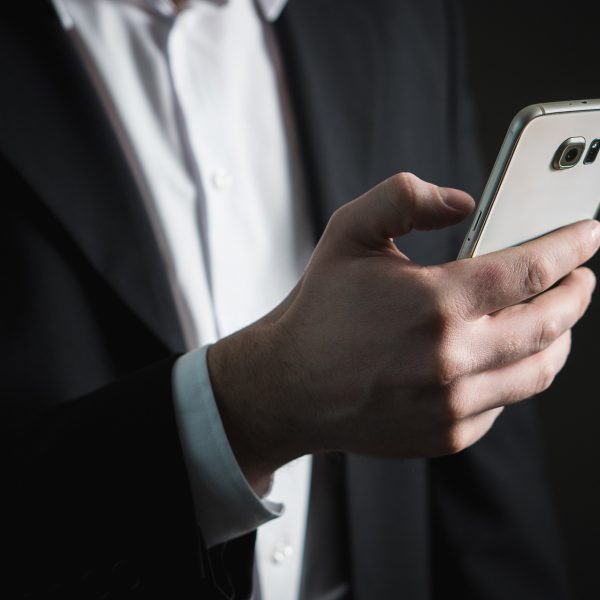 A man in a business suit browses his smartphone.