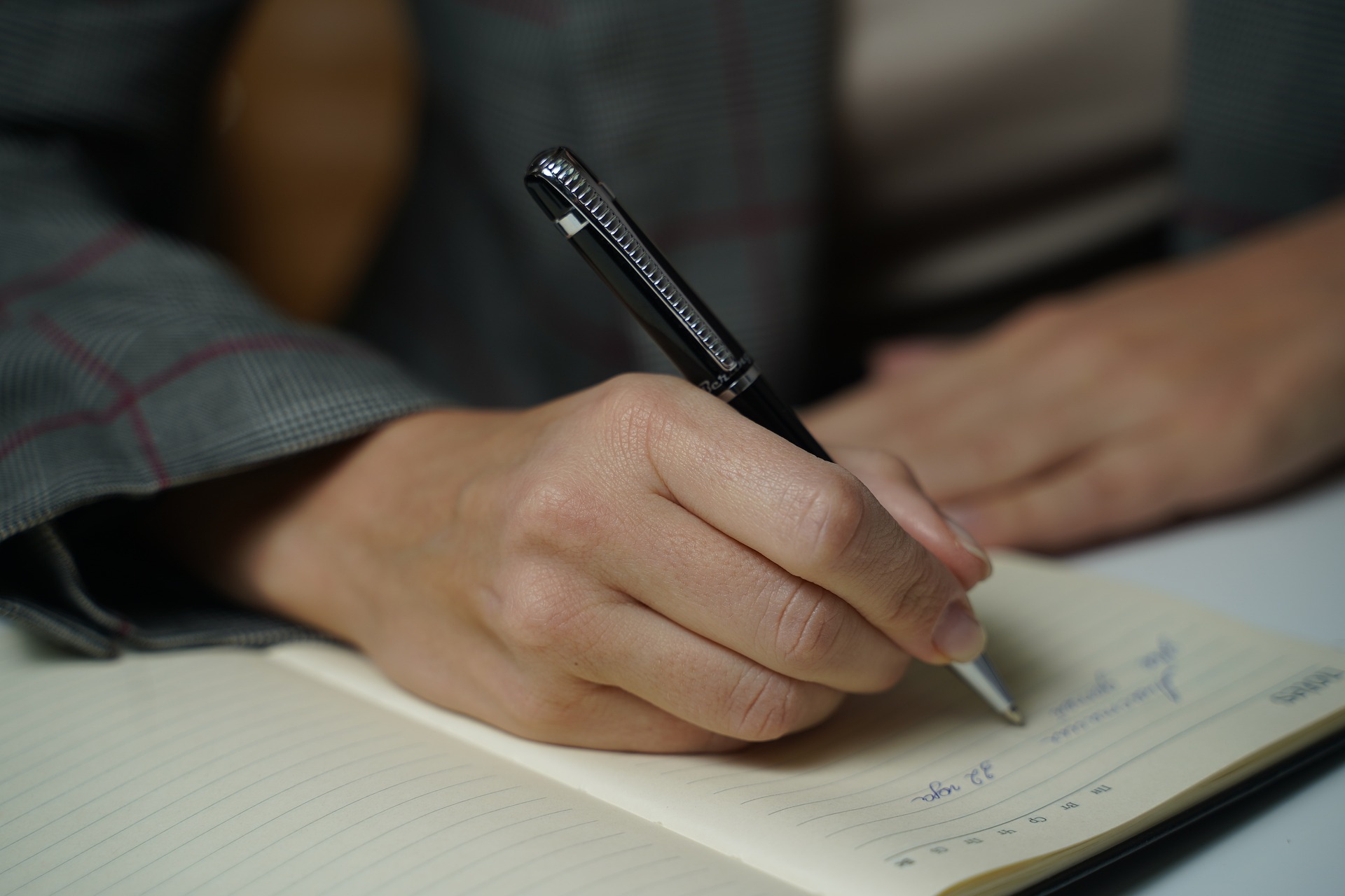 A hand writing in a notebook.