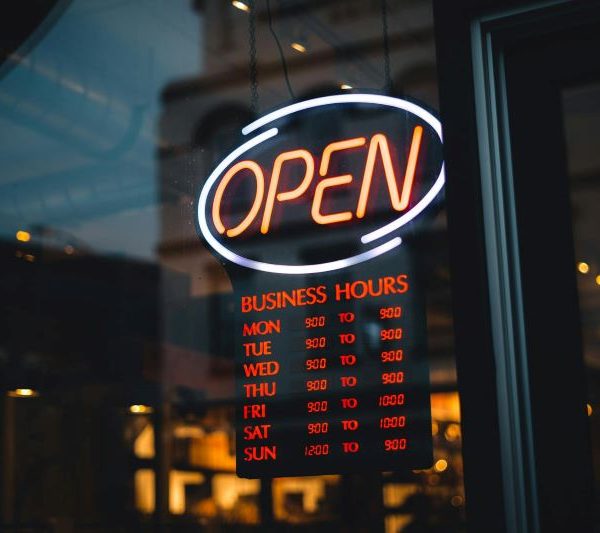 An open sign on a store, with the hours of operation.