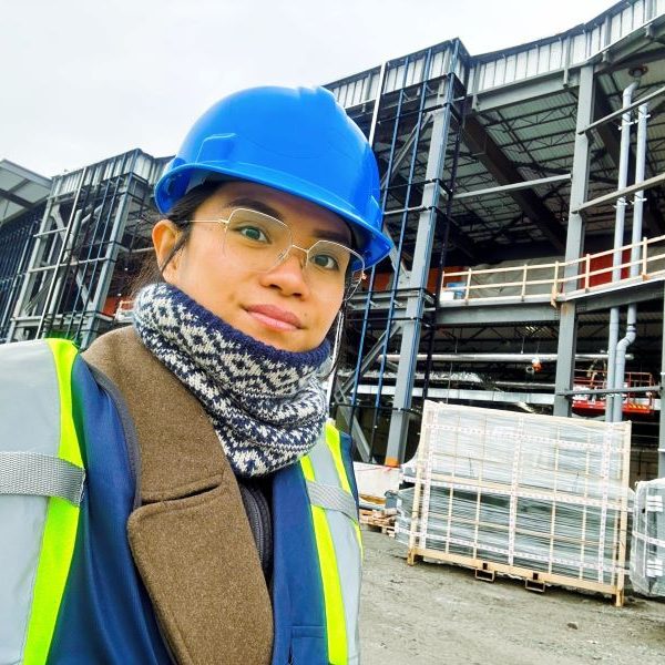 Eliana wearing a hardhat and high-viz vest on a jobsite.