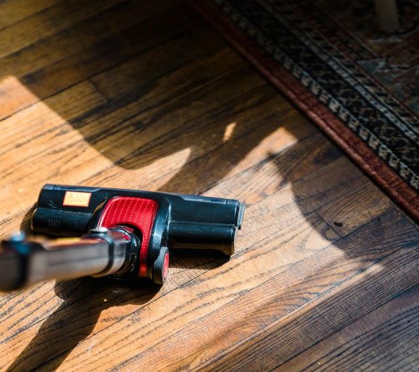 A person uses a vaccuum to clean the floor.