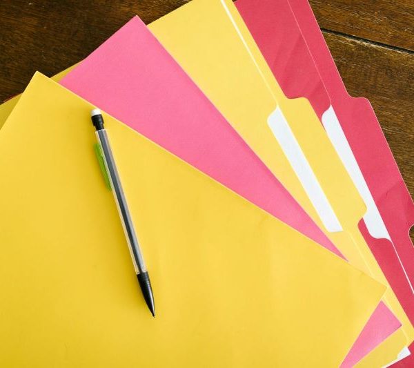 Folders on a table with a pencil on top.