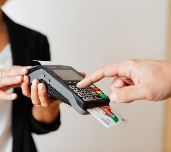 A cashier holds a payment terminal, which a customer has a card inserted into to pay.