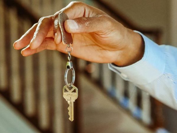 A man holds a house key on a chain.