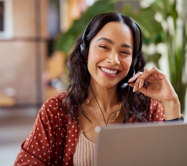 A woman wearing a headset uses a laptop.