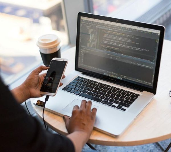 A woman goes on the phone while writing code on her laptop