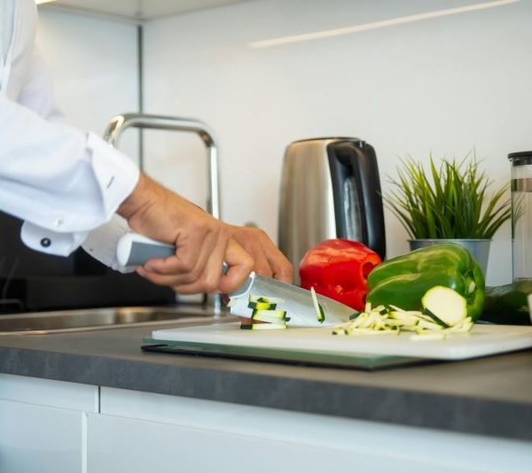 A chef cuts vegetables in a kitchen.